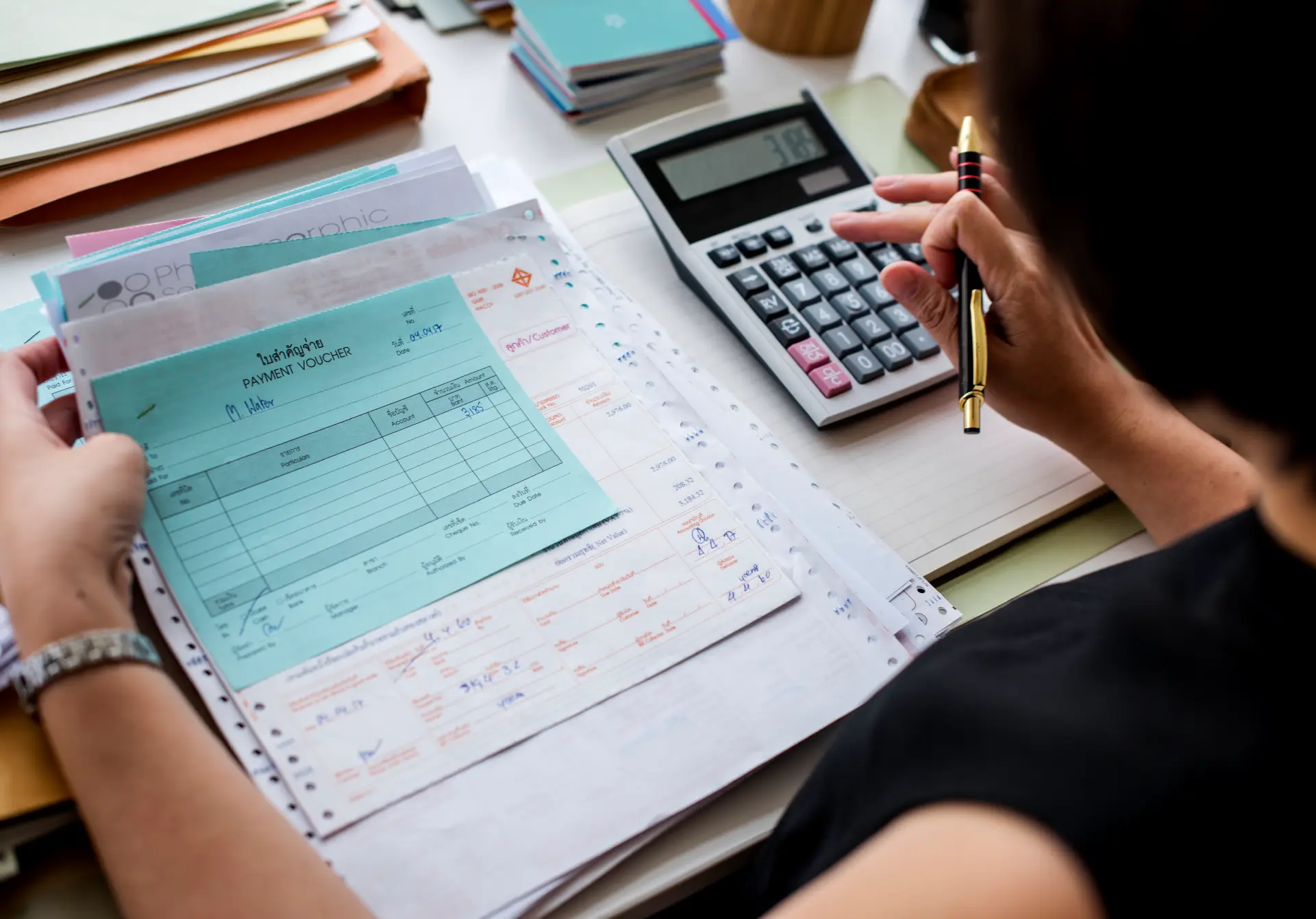 Persona revisando comprobantes de pago y facturas con una calculadora sobre el escritorio